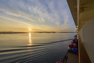 View from a cruise ship, Mein Schiff 6, of the calm sea at sunrise with soft clouds in the sky,