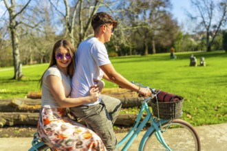 Romantic couple riding a bicycle together on a sunny day, enjoying the lush greenery of a vibrant