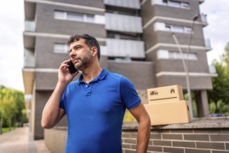 Delivery man talking to the mobile next to parcels to deliver outdoors