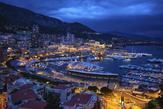Aerial view of Monaco Monte Carlo harbour and illuminated city skyline in the evening blue hour