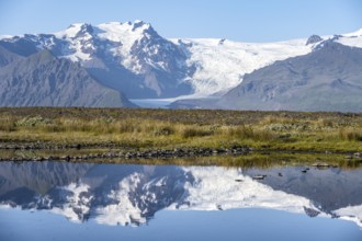 Reflection in a lake, view of Svínafellskökull glacier tongue, glaciated mountain peak