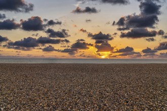 Empty pebble beach by the sea, sunset on the horizon