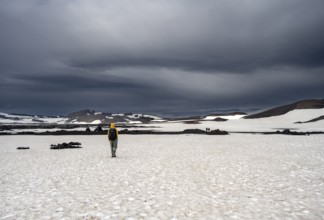 Hikers in snow-covered volcanic landscape with volcanic sand and petrified lava, crater of Askja