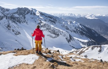 Ski tourer standing next to summit cross, summit of Mitterzeigerkogel in winter, Sellraintal,