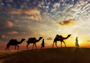 Travel background, two cameleers (camel drivers) with camels silhouettes in dunes of desert on