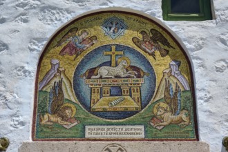 A religious mosaic with Christian symbols and angels, decorating a stone wall in a Catholic church,
