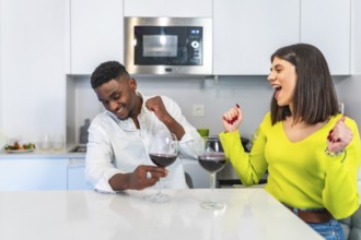 Multiethnic couple shares a joyful moment cooking burgers and drinking wine in a modern kitchen,