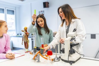 High school students learning chemistry with their teacher, using test tubes, flasks and microscope
