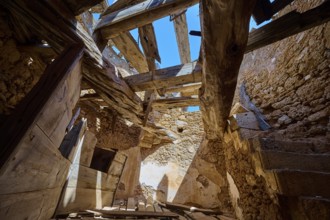 The interior of a crumbling mill with damaged wooden beams and a view of the blue sky, windmill,