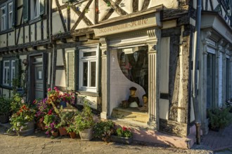 Idyllic old half-timbered house with floral decorations and shop window of milliner, milliner, hat