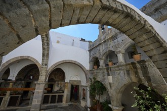 Historic courtyard with stone arches and white walls in a Mediterranean atmosphere, Agiou Theologou