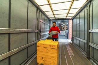 View from inside the vehicle of a male latin warehouse worker loading a truck using hydraulic hand