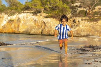 Carefree child enjoying summer holidays, running along the shore of s'amarador beach in mallorca,