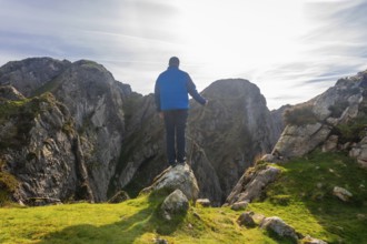 Hiker standing on a rock enjoying the breathtaking landscape of mount penas de aya in oiartzun, a