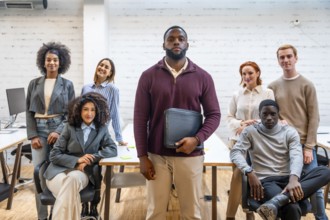 Serious african man standing in a coworking surrounded by colleagues in a modern office
