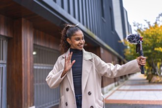 Afro beauty woman streaming online waving at camera outdoors in the city