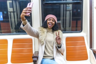 Cheerful young woman smiling and taking a selfie with a peace sign while enjoying her commute on