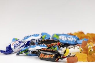 Mix of various branded sweets and gummy bears on a white background