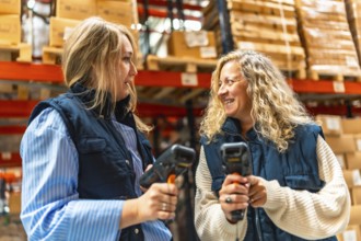 Two female blonde coworkers talking while using barcode scan readers in a distribution warehouse