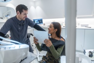 Dentist discussing teeth scan results with a smiling patient, showcasing modern dental technology