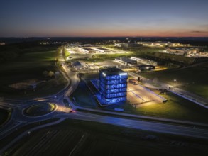 Illuminated modern building in an industrial area at night with a view of illuminated streets,