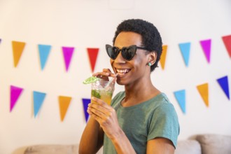 Latin cool man sucking a straw drinking cocktail partying at home