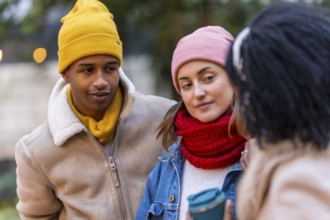 Three friends wearing winter clothes are enjoying a walk together in the city, sharing a