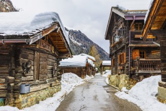 Street with historic old snow-covered wooden houses, mountain village of Zinal, Val d'Anniviers,