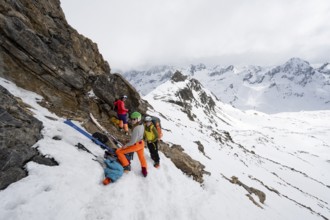Three mountaineers at the ski depot of Piz Laviner, view of mountain panorama in wintry mountain