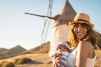 Mother with a baby in arms visiting traditional windmills in Cabo de Gata, Spain, Europe