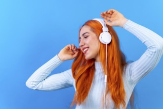 Redhead woman in studio photography smiling dancing on a blue background