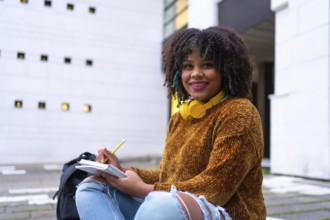 Portrait of black ethnic girl sitting in college doing classwork or studying for an exam on back to