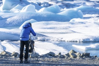 A photographer photographs floating icebergs in the Jokulsarlon glacier lagoon in Iceland
