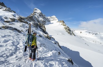 Mountaineer with skis at the fork Porta d'Es-cha, view of mountain peak Piz Kesch and glacier