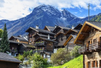 Old wooden houses in the historic village centre, behind the summit of the Scex Marenda mountain,