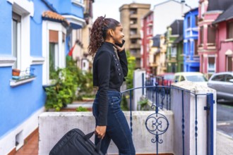 African american casual businesswoman carrying laptop bag and talking to the mobile phone leaving