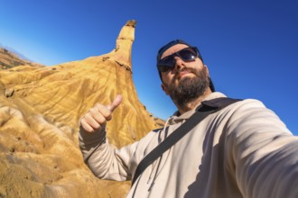 Tourist making thumbs up sign enjoying the view of the geological formations in bardenas reales