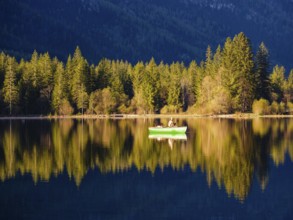 Angler in a rowing boat on the Hintersee in the first sunlight, Berchtesgaden National Park,