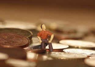 Miniature man sitting among euro coins, North Rhine-Westphalia, Germany, Europe