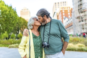 Frontal portrait of a senior couple kissing while visiting a city