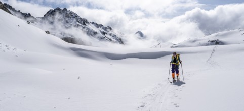 Atmospheric clouds in a wintry mountain landscape, ski tourer on the ascent to Porta d'Es-cha,