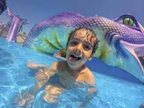 Happy child sticking out his tongue, enjoying playful moments at a vibrant water park during a