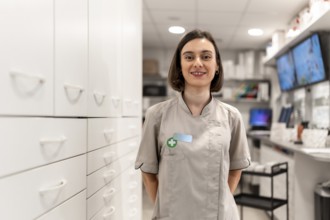 Young and proud female pharmacist standing with arms in the back in the storage room in a modern