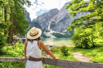 Woman wearing straw hat enjoying majestic view of lake braies - lago di braies or pragser wildsee -