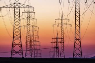High-voltage pylons, overhead power lines at sunset. Schwieberdingen, Baden-Württemberg, Germany,
