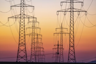 High-voltage pylons, overhead power lines at sunset. Schwieberdingen, Baden-Württemberg, Germany,