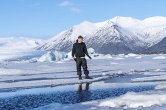 An adventurous young man walking on the frozen Jokulsarlon lake in winter in Iceland