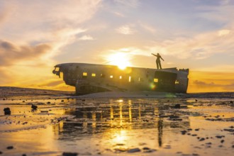 Woman waving atop the Solheimasandur plane on a winter sunrise in Iceland