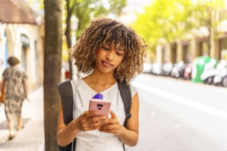 Latin beauty young woman looking down while using phone standing in the street