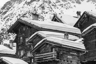 Old snow-covered wooden houses in the historic village centre, black and white photograph,